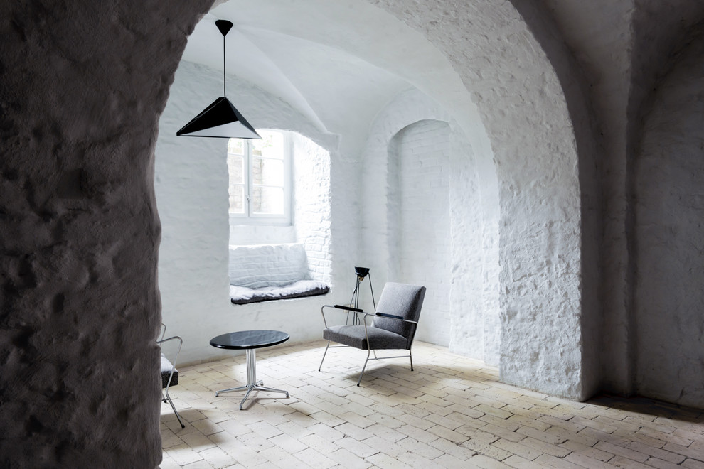 Modelo de sala de estar abierta urbana pequeña sin chimenea y televisor con paredes blancas, suelo de ladrillo y suelo beige