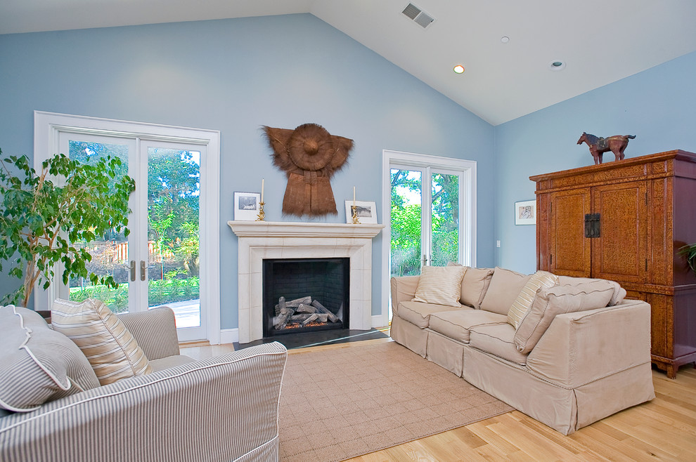 Источник вдохновения для домашнего уюта: открытая гостиная комната среднего размера в стиле кантри с синими стенами, светлым паркетным полом, стандартным камином и фасадом камина из камня