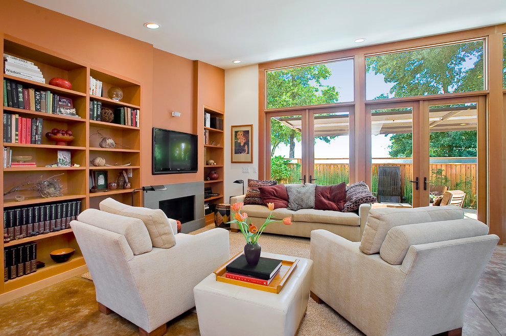 На фото: маленькая открытая гостиная комната в современном стиле с оранжевыми стенами, бетонным полом, горизонтальным камином, фасадом камина из бетона и телевизором на стене для на участке и в саду с