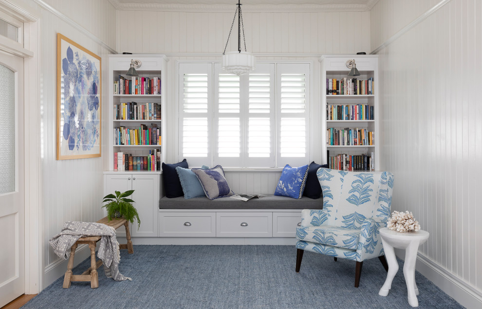 Klassisk inredning av ett mellanstort allrum med öppen planlösning, med ett bibliotek, vita väggar, heltäckningsmatta och blått golv