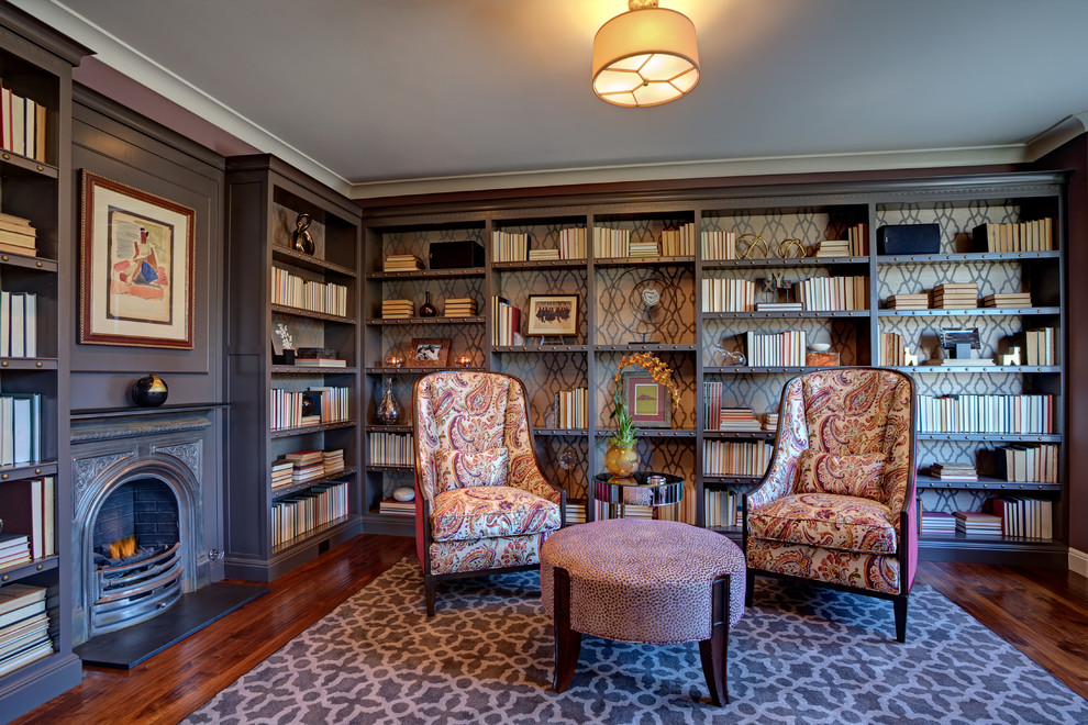 Cette image montre une salle de séjour traditionnelle de taille moyenne et fermée avec une bibliothèque ou un coin lecture, un mur violet, un sol en bois brun, une cheminée standard et un manteau de cheminée en métal.