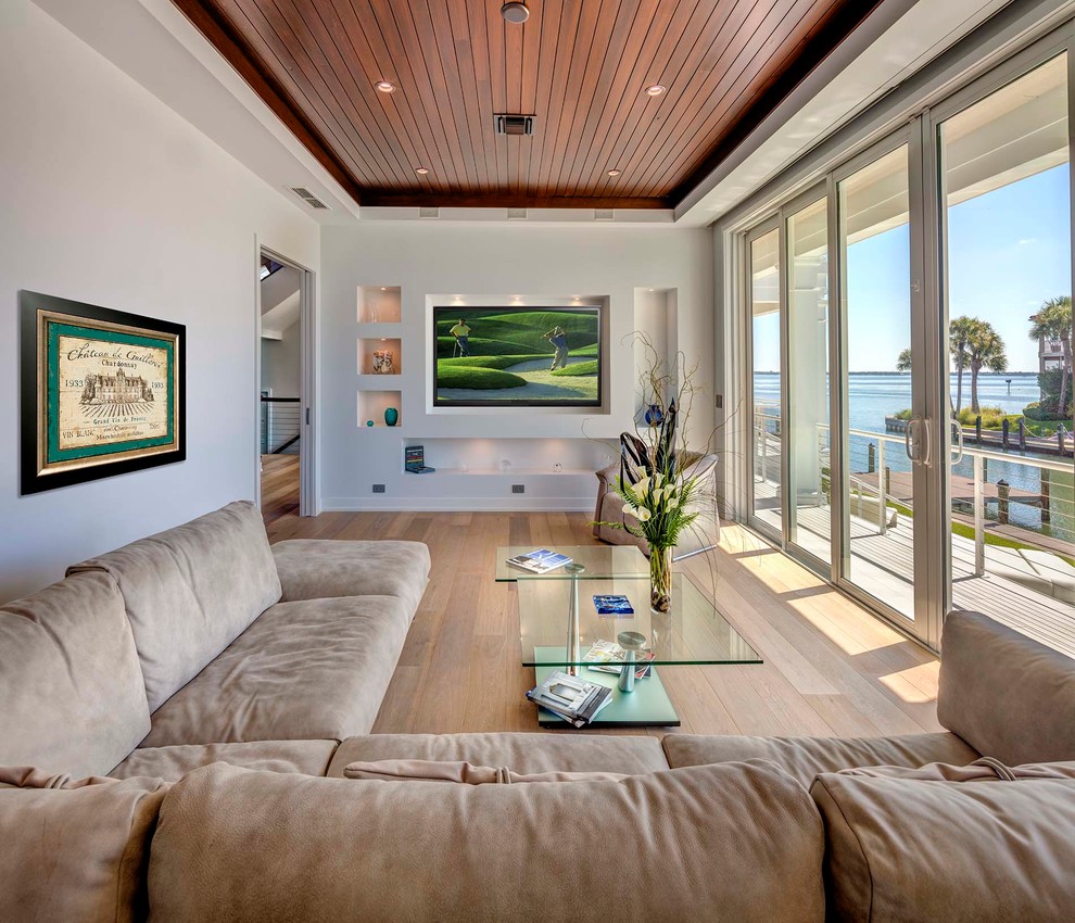 Inspiration for a mid-sized coastal light wood floor family room remodel in Tampa with no fireplace and a media wall