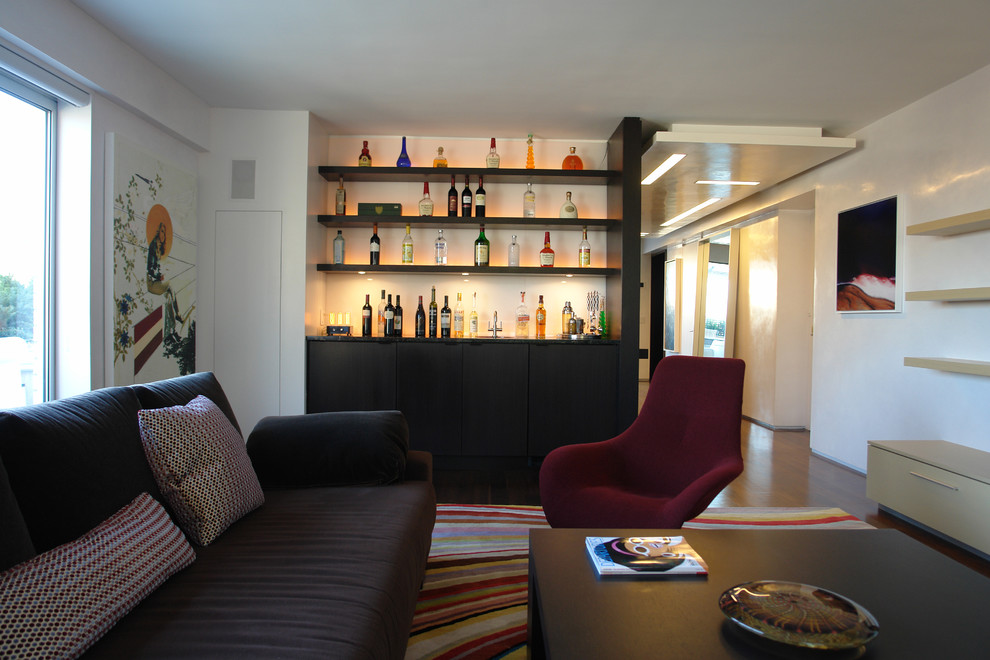 Cette image montre une grande salle de séjour design ouverte avec un bar de salon, un mur violet, parquet foncé, un téléviseur fixé au mur, aucune cheminée et un sol marron.