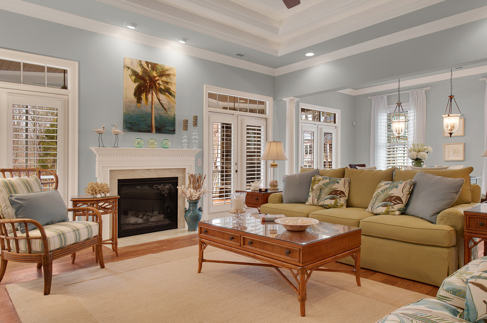 Diseño de sala de estar abierta marinera grande con paredes azules, suelo de madera clara, todas las chimeneas y marco de chimenea de piedra