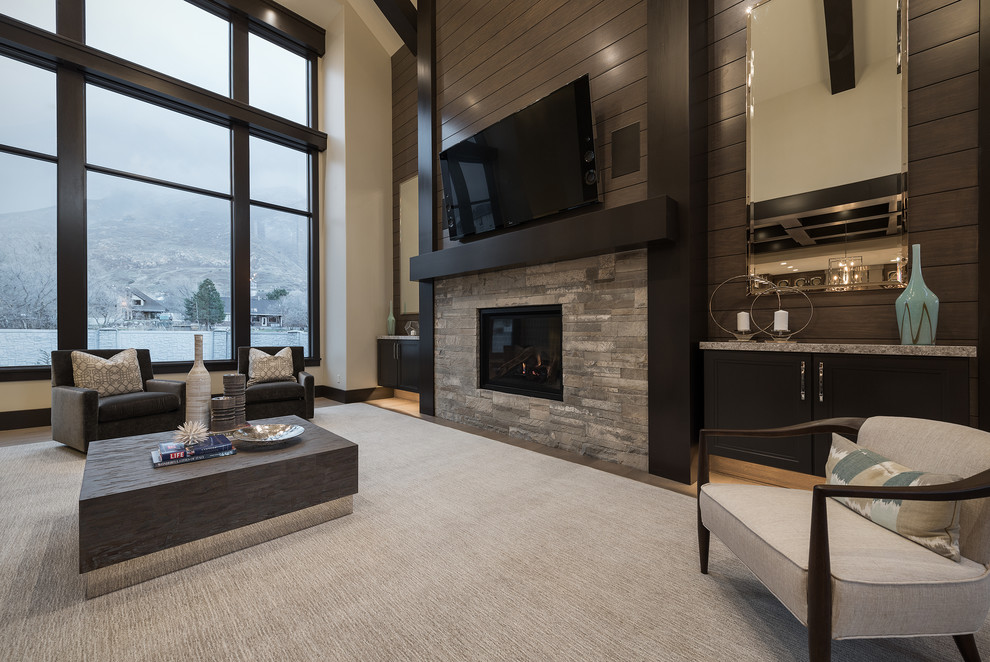 Photo of a large modern open plan games room in Salt Lake City with beige walls, carpet, a standard fireplace, a wall mounted tv and a stone fireplace surround.