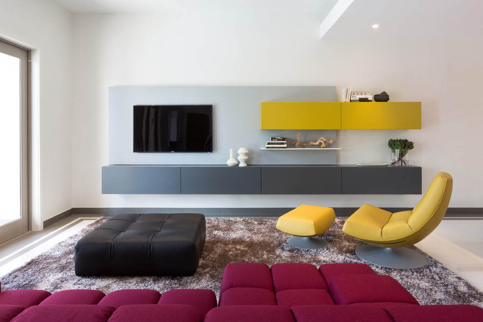 Imagen de sala de estar abierta actual grande con paredes blancas, suelo de baldosas de porcelana y televisor colgado en la pared