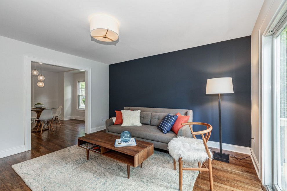 Imagen de sala de estar abierta tradicional renovada con paredes azules, suelo de madera en tonos medios, televisor colgado en la pared y suelo marrón