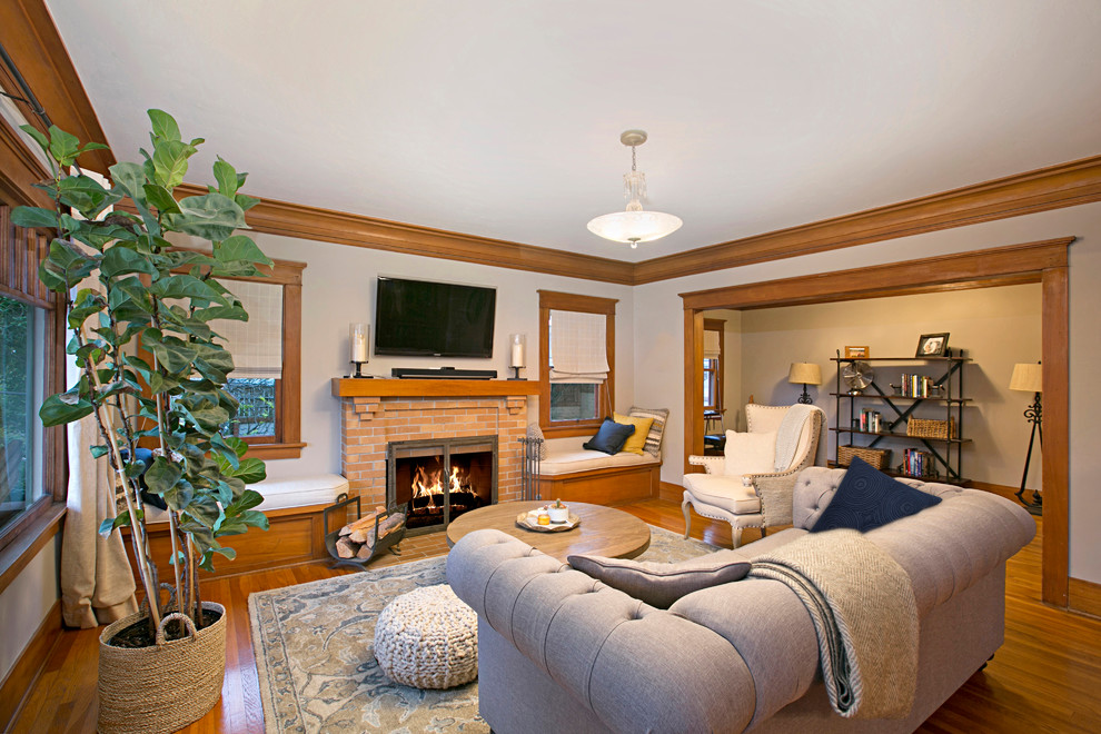 Example of a mid-sized arts and crafts enclosed light wood floor and brown floor family room design in Denver with gray walls, a standard fireplace, a brick fireplace and a wall-mounted tv