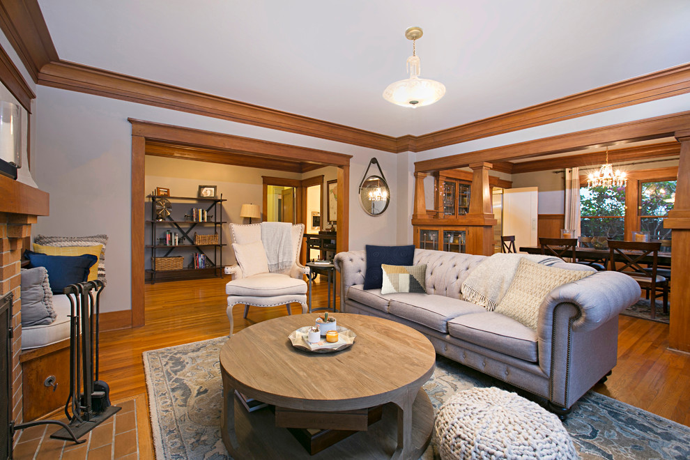 На фото: изолированная гостиная комната среднего размера в стиле кантри с серыми стенами, стандартным камином, фасадом камина из кирпича, телевизором на стене, паркетным полом среднего тона и коричневым полом с