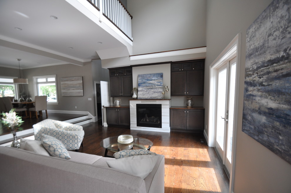 Идея дизайна: большая гостиная комната в стиле неоклассика (современная классика) с серыми стенами, темным паркетным полом, фасадом камина из плитки и коричневым полом