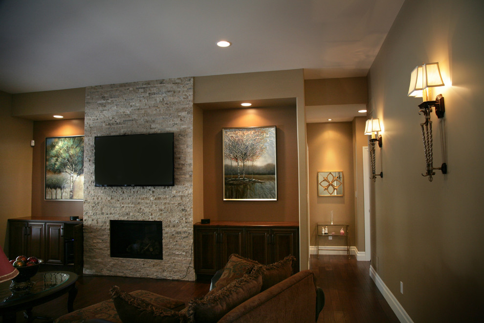 Imagen de sala de estar abierta clásica renovada con paredes marrones, suelo de madera oscura, todas las chimeneas, marco de chimenea de piedra y televisor colgado en la pared
