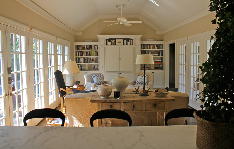 Imagen de sala de estar con biblioteca abierta bohemia de tamaño medio sin chimenea con paredes beige, suelo de madera oscura y pared multimedia
