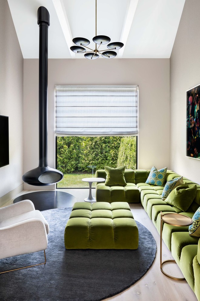 Diseño de sala de estar campestre con chimeneas suspendidas, televisor colgado en la pared, paredes beige y suelo de madera clara