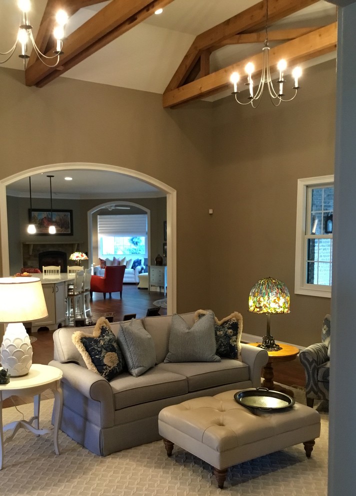 Cette photo montre une grande salle de séjour craftsman ouverte avec un mur gris, un sol en bois brun, une cheminée d'angle, un manteau de cheminée en bois et un téléviseur fixé au mur.