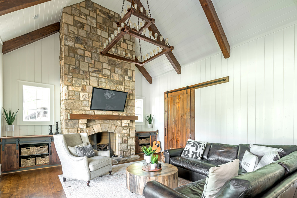 Inspiration pour une salle de séjour marine fermée avec un sol en bois brun, une cheminée standard, un manteau de cheminée en pierre et un téléviseur fixé au mur.