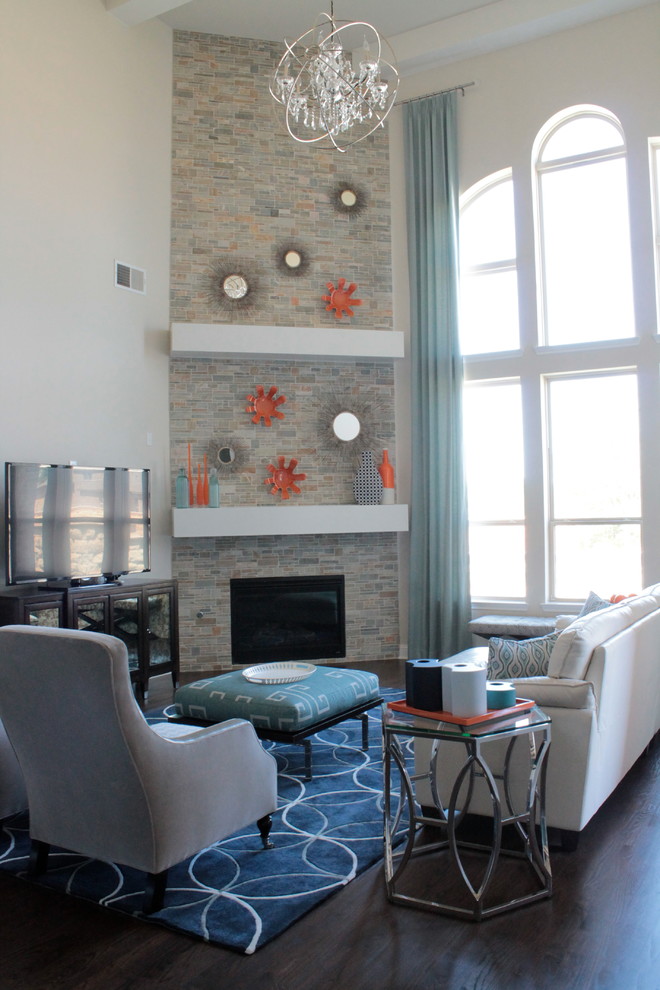 Imagen de sala de estar abierta actual grande con paredes beige, suelo de madera oscura, chimenea de esquina, marco de chimenea de piedra y televisor independiente