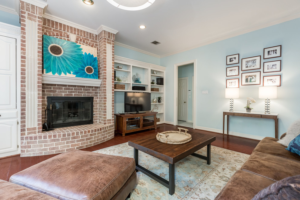 Inspiration pour une grande salle de séjour traditionnelle avec un mur bleu, parquet foncé, une cheminée standard, un manteau de cheminée en brique et un téléviseur indépendant.