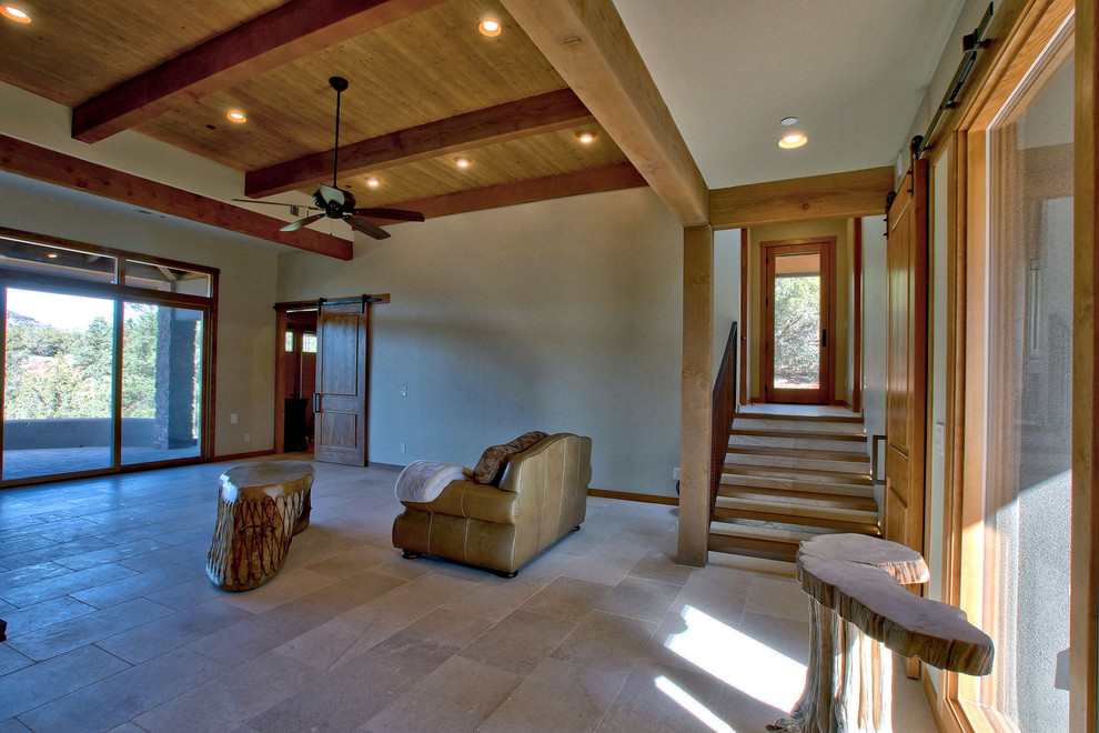 Rural open plan games room in Other with limestone flooring, a two-sided fireplace, a stone fireplace surround and white floors.