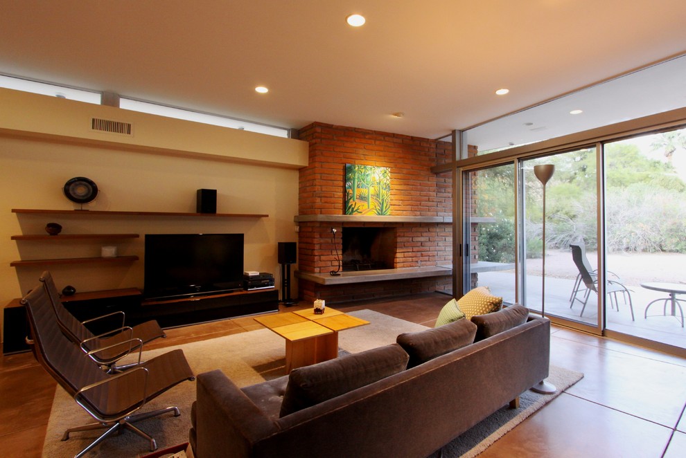 Example of a minimalist concrete floor family room design in Phoenix with a standard fireplace and a brick fireplace