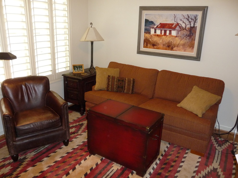 Ejemplo de sala de estar con biblioteca cerrada de estilo americano pequeña sin chimenea con paredes beige, moqueta, televisor retractable y suelo marrón
