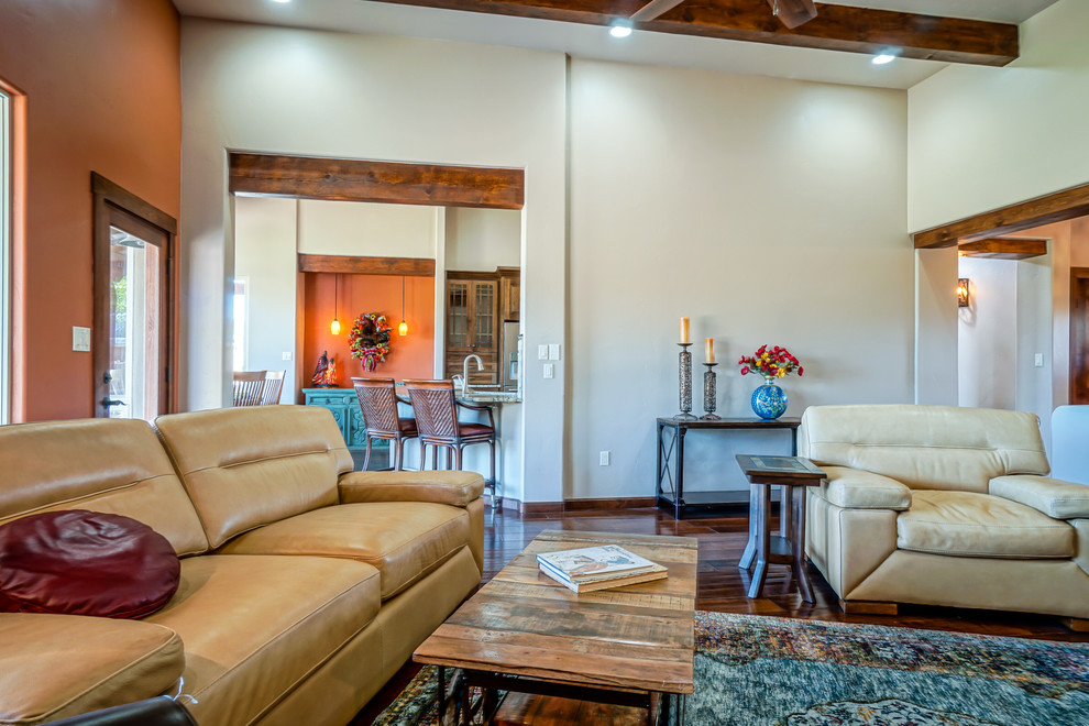 Exemple d'une grande salle de séjour sud-ouest américain ouverte avec un mur beige, parquet foncé, une cheminée standard, un manteau de cheminée en carrelage et un sol marron.