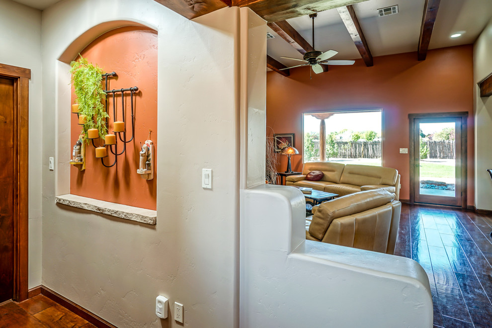 Cette image montre une grande salle de séjour sud-ouest américain ouverte avec un mur beige, parquet foncé, une cheminée standard, un manteau de cheminée en carrelage et un sol marron.
