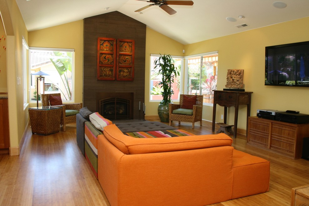 Foto di un soggiorno chic di medie dimensioni e aperto con pareti gialle, pavimento in bambù, camino classico, cornice del camino in pietra e TV a parete