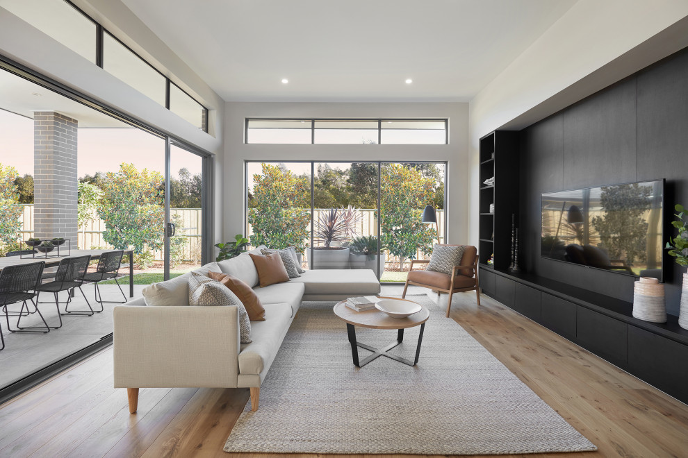 Источник вдохновения для домашнего уюта: открытая гостиная комната в современном стиле с телевизором на стене без камина