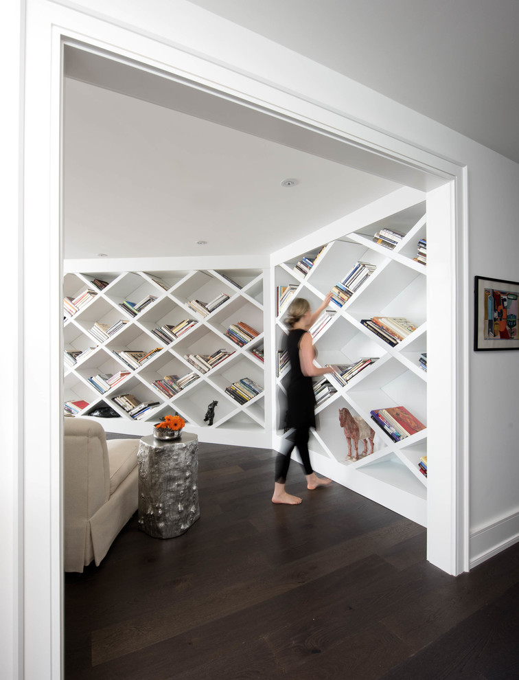 Cette image montre une salle de séjour design de taille moyenne et ouverte avec une bibliothèque ou un coin lecture, un mur blanc et parquet foncé.