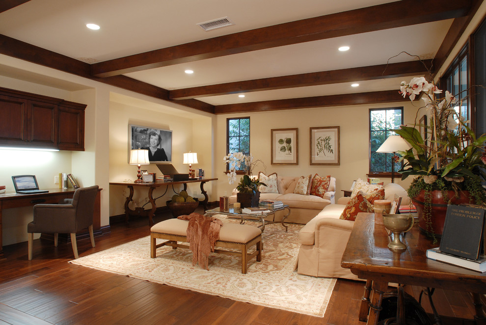 Modelo de sala de estar mediterránea con paredes beige, suelo de madera en tonos medios, televisor colgado en la pared y alfombra
