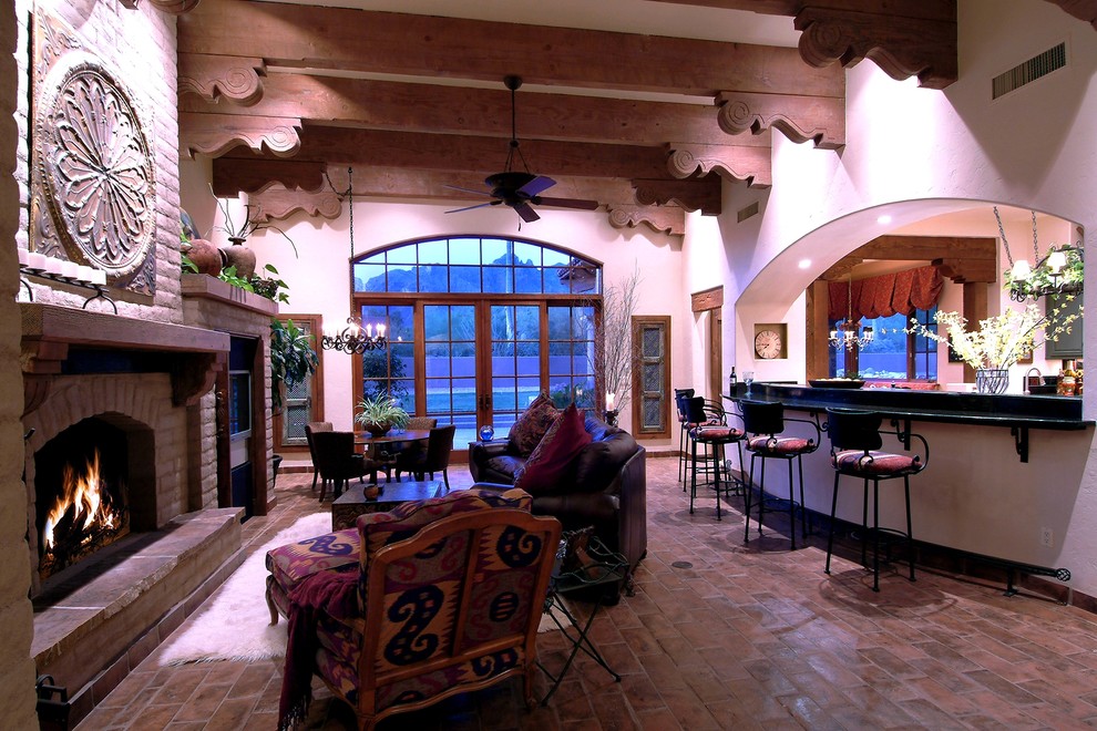 Family room - mid-sized southwestern enclosed terra-cotta tile family room idea in Phoenix with a bar, beige walls, a standard fireplace and a stone fireplace