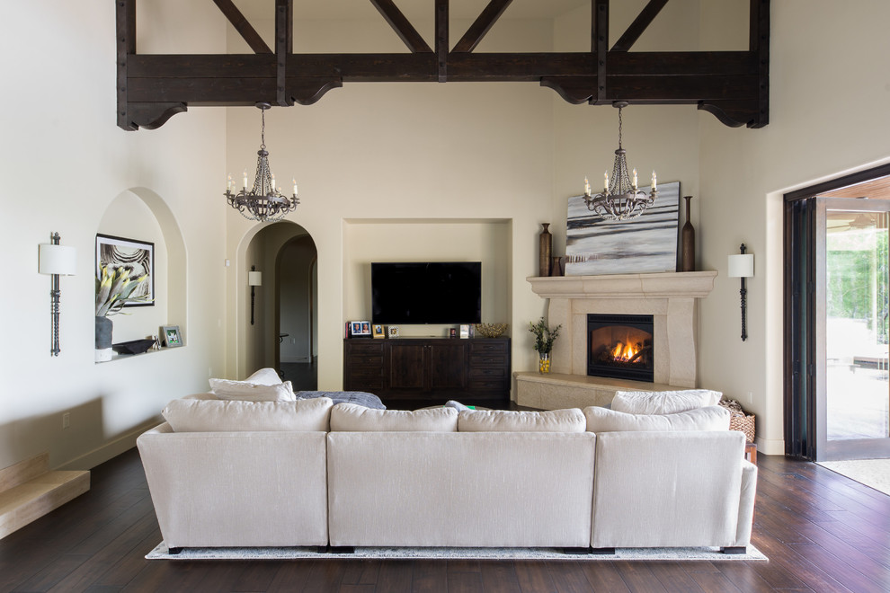 Inspiration for a mediterranean games room in San Luis Obispo with beige walls, dark hardwood flooring, a corner fireplace, a wall mounted tv and brown floors.