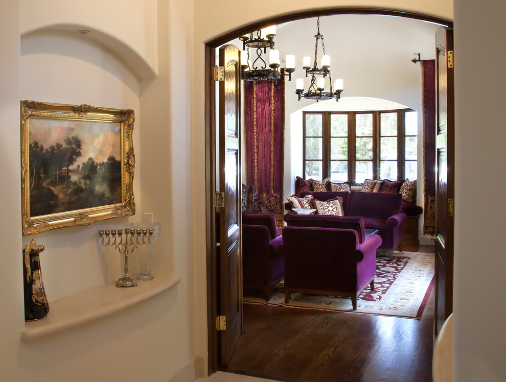 Пример оригинального дизайна: огромная открытая гостиная комната в средиземноморском стиле с с книжными шкафами и полками, белыми стенами и темным паркетным полом без телевизора