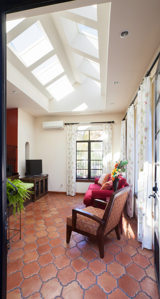 Imagen de sala de estar abierta mediterránea de tamaño medio sin chimenea con paredes blancas, suelo de baldosas de terracota, televisor independiente y suelo naranja