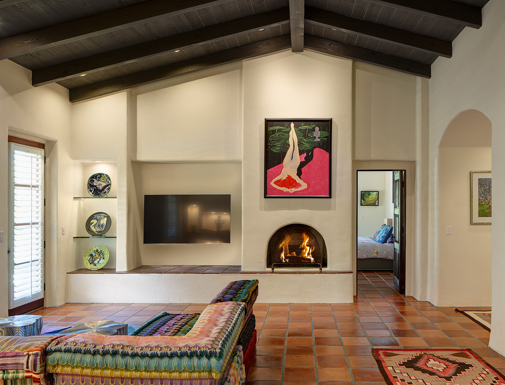Idée de décoration pour une salle de séjour sud-ouest américain avec tomettes au sol, un poêle à bois et un manteau de cheminée en plâtre.