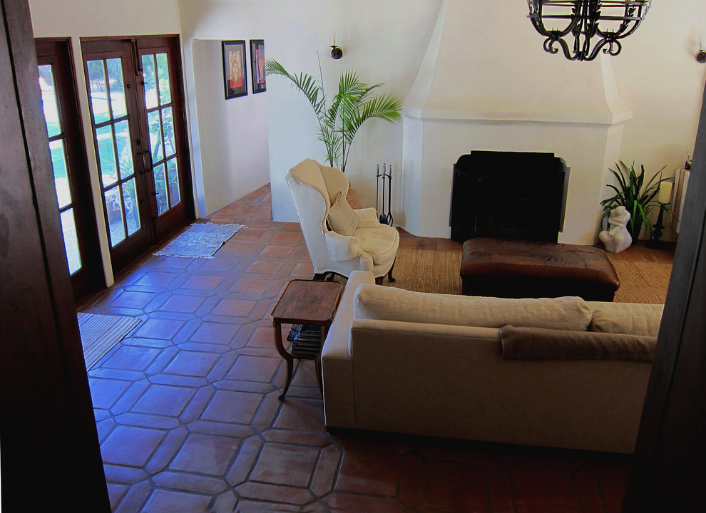 Источник вдохновения для домашнего уюта: изолированная гостиная комната среднего размера в средиземноморском стиле с белыми стенами, полом из терракотовой плитки, стандартным камином, фасадом камина из бетона и красным полом