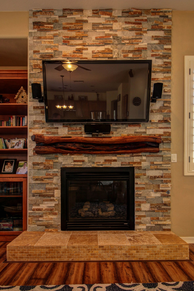 Foto de sala de estar clásica renovada con marco de chimenea de piedra, paredes beige, suelo de madera en tonos medios y todas las chimeneas