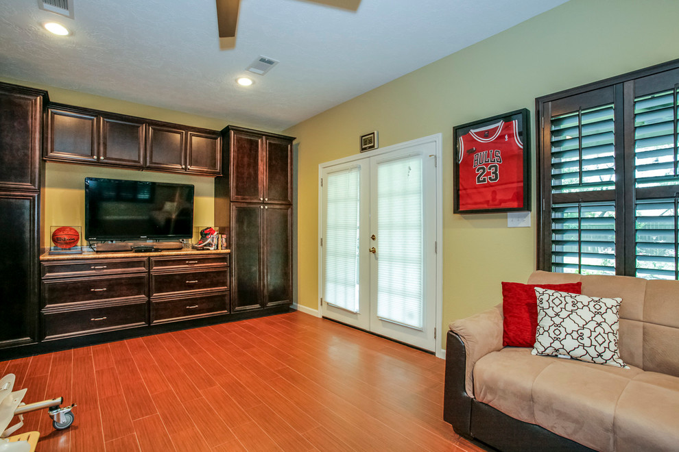 Immagine di un grande soggiorno classico con pareti gialle, pavimento in laminato e TV autoportante