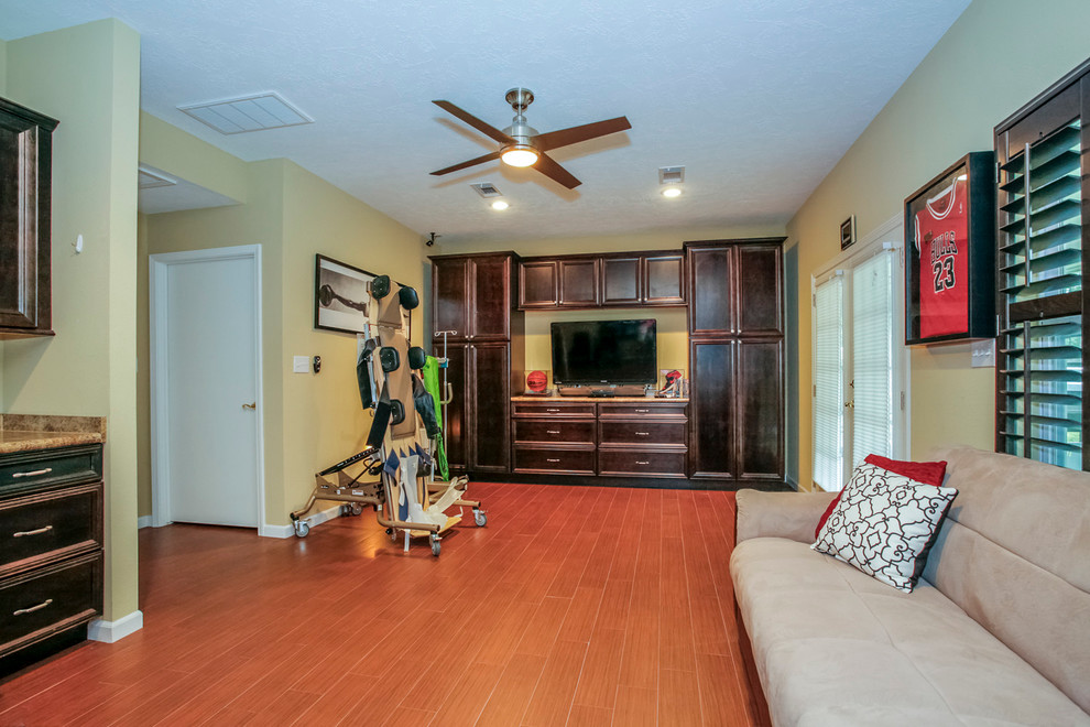Large classic games room in Houston with yellow walls, laminate floors and a freestanding tv.