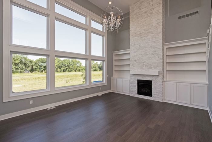 Example of a large trendy open concept medium tone wood floor family room design in Other with gray walls, a standard fireplace, a stone fireplace and no tv