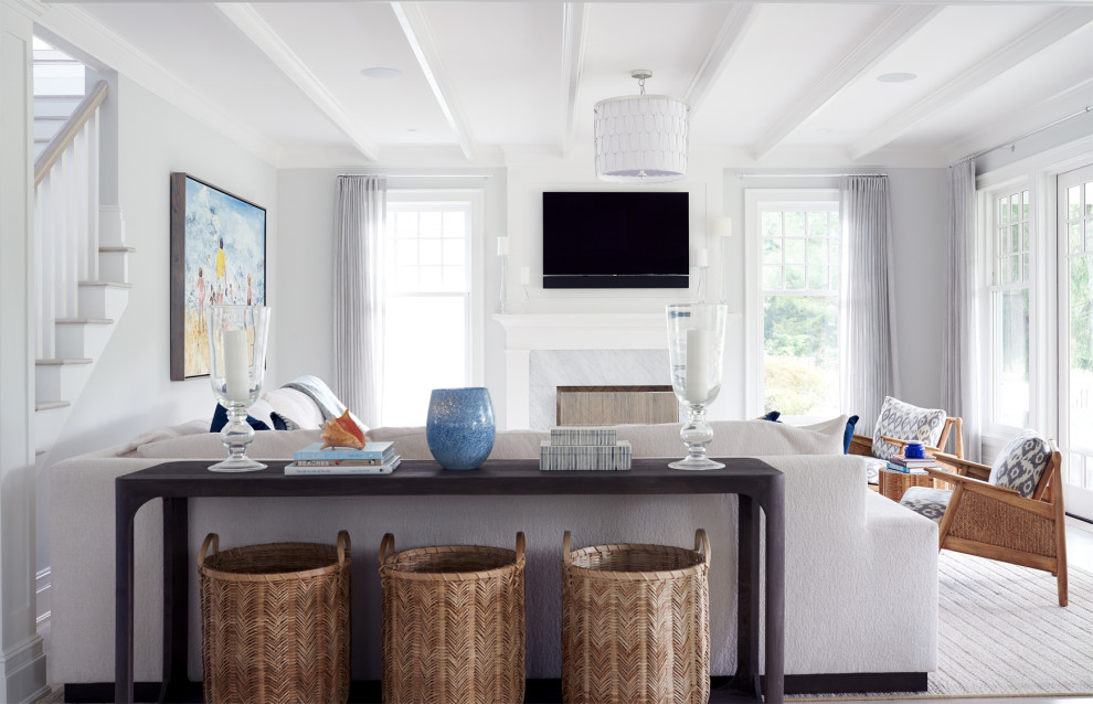 На фото: гостиная комната в морском стиле с серыми стенами, светлым паркетным полом, стандартным камином, фасадом камина из камня и телевизором на стене