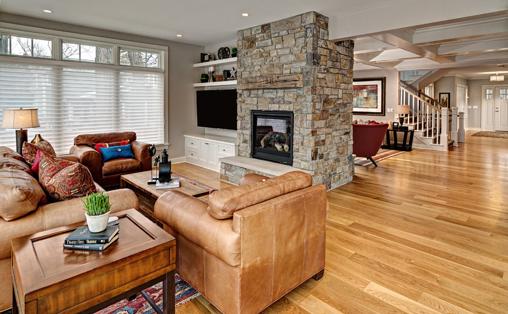 Imagen de sala de estar tradicional renovada con suelo de madera clara, todas las chimeneas y marco de chimenea de piedra