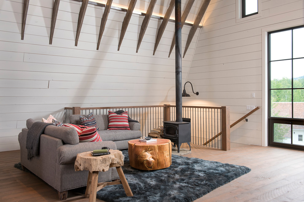 Imagen de sala de estar abierta de estilo de casa de campo de tamaño medio sin televisor con paredes beige, suelo de madera clara y estufa de leña