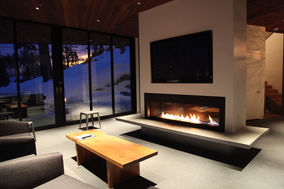 Cette photo montre une grande salle de séjour tendance avec un mur blanc, sol en béton ciré, un téléviseur fixé au mur, une cheminée ribbon et un manteau de cheminée en plâtre.