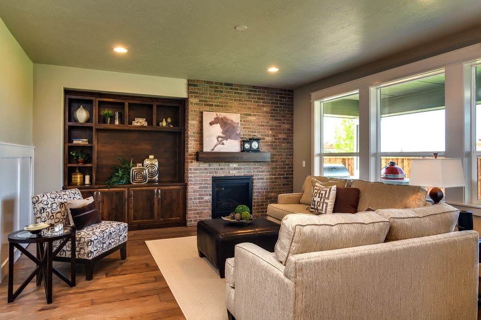 Cette image montre une grande salle de séjour traditionnelle fermée avec un mur vert, un sol en bois brun, une cheminée standard et un manteau de cheminée en brique.