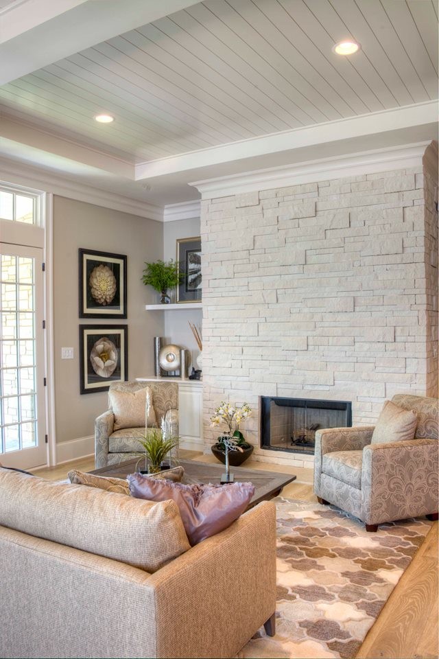Imagen de sala de estar abierta ecléctica de tamaño medio con paredes grises, suelo de madera clara, todas las chimeneas y marco de chimenea de piedra