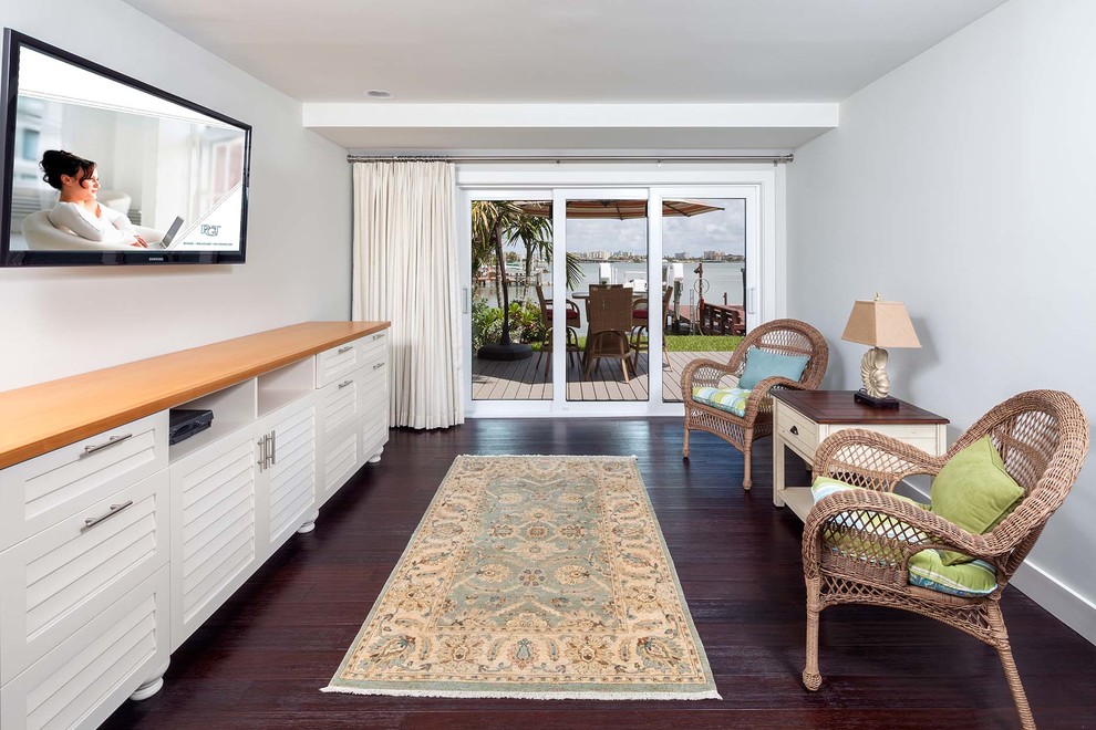 Mittelgroßes, Offenes Wohnzimmer ohne Kamin mit grüner Wandfarbe, braunem Holzboden, TV-Wand und braunem Boden in Tampa