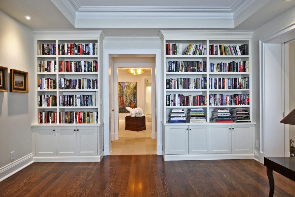 Exemple d'une salle de séjour chic de taille moyenne et fermée avec une bibliothèque ou un coin lecture, un mur beige, parquet foncé, aucune cheminée, un téléviseur fixé au mur et un sol marron.