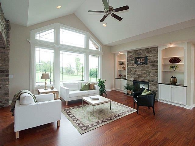 Large trendy open concept medium tone wood floor family room photo in Detroit with beige walls, a standard fireplace, a stone fireplace and no tv