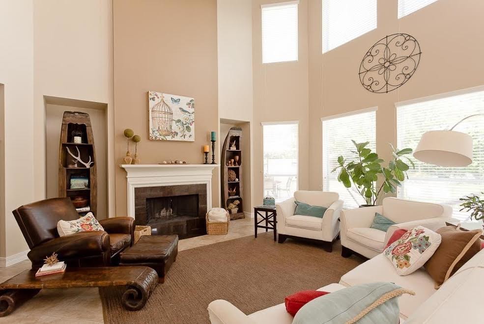 Modelo de sala de estar abierta clásica grande con paredes beige, suelo de baldosas de cerámica, todas las chimeneas, televisor retractable, marco de chimenea de madera y suelo beige